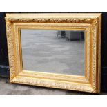 A large modern gilt framed wall mirror, with two heavily plaster applied borders, with flowers and v