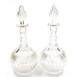 A pair of early 20thC cut glass decanters, with slender slice cut necks and spherical bodies, with p