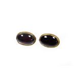 A pair of garnet set stud earrings, each with a rub over rope twist yellow metal border, unmarked la