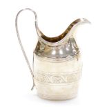 A George III crested silver cream jug, with strapwork handle and oval body engraved with a family cr