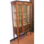 An Edwardian mahogany and boxwood strung serpentine display cabinet, the fixed cornice set with a fl