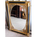 A large rectangular ornate wall mirror, with oval inset mirror glass panel, with a gold silvered and