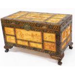 A modern Oriental camphor wood style chest, the top with various lightwood panels, on leaf carved si