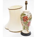 A Moorcroft table lamp, in cream decoration with berries and flowers, on mahogany base, with Moorcro