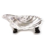 A George V shell shaped butter dish, of shaped form with raised garland handle on triple dolphin fee