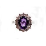 A 18ct white gold amethyst and diamond cluster ring, the central oval amethyst totalling approximat