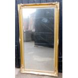 A large rectangular wall mirror, the gilt borders with scroll decoration, 137cm high, 73cm wide.