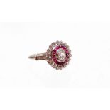 An Edwardian style ruby and diamond cluster ring, with central old cut diamond surrounded by calibre