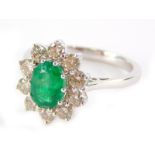 An 18ct white gold oval emerald and diamond cluster ring, the oval cut emerald totalling approx 1.20