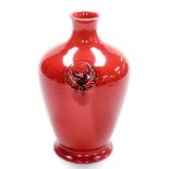 A William Moorcroft vase, on a red ground with circular emblem, signed to underside, 22cm high.