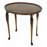 A 20thC mahogany finished occasional table, the oval pie crust top raised on quadruple legs, carved