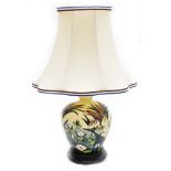 A Moorcroft table lamp, decorated with lilies, on a cream ground, on stepped mahogany base, with sha