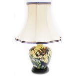 A Moorcroft table lamp, decorated with lilies, on a cream ground, on stepped mahogany base, with sha