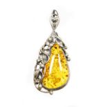 A silver and amber pendant, the pear cut amber stone, surrounded by vines of flowers and leaves, in
