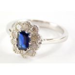 An 18ct white gold sapphire and diamond cluster ring, with a rectangular cut sapphire totalling appr