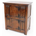 A 20thC oak cupboard in the manner of Titmarsh and Goodwin, set with two doors flanked by linen fold