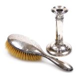 Two items of silverware, to include a silver backed dressing table brush and a candlestick, each wit