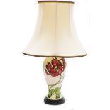 A Moorcroft table lamp, in cream decoration with red flowers and green leaves on a stepped mahogany