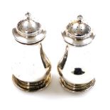 A pair of George V silver pepper pots, each with compressed domed lids, baluster bodies and stepped