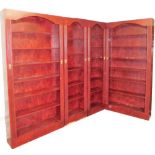 A red stained finish bookcase set, comprising two large bookcase sections and two thinner sections a