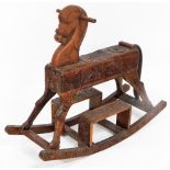 A Nepalese carved rocking horse, heavily carved floral decoration, 75cm high, 90cm long, 32cm wide.