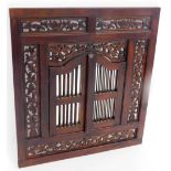 A stained wooden pierced wall mirror, the rectangular frame with scroll and vase carved decoration w