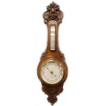 An early 20thC carved oak android barometer, the dial stamped J E Beale of Bournemouth, 78cm high.