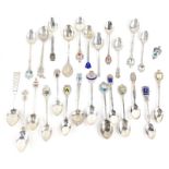 A quantity of continental white metal souvenir spoons, some with enamel decoration.