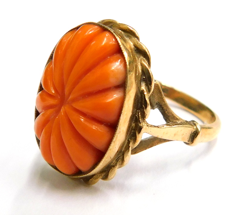 A 9ct gold dress ring, with central oval cut in coral, and twist design border, on a splayed and rai
