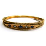 A Victorian 15ct gold hinged bangle, with a diamond shaped top section set, with sapphires and diamo