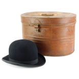 A late 19th/early 20thC brown painted tin oval hat box, and a bowler hat stamped New Model. (2)