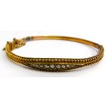 A Victorian hinged bangle, the half hoop design with reeded filigree type decoration, with central d