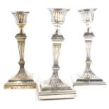 A set of three late Victorian silver candlesticks, each with fluted decoration to the sconce, stem a