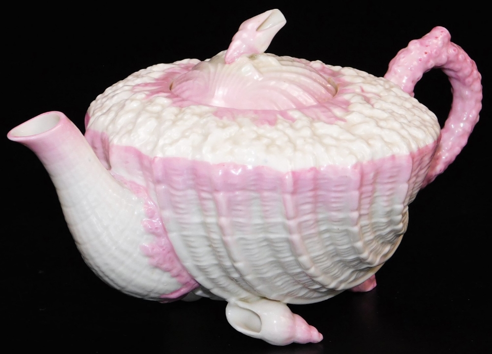 A first period Belleek pink ground Neptune teapot and cover, the coral moulded body sitting on shell