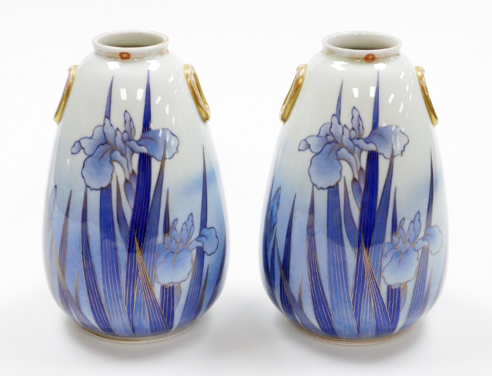 A pair of Japanese vases, each with gilt applied handles and a floral stemmed rim, on a blue wash gr