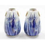 A pair of Japanese vases, each with gilt applied handles and a floral stemmed rim, on a blue wash gr