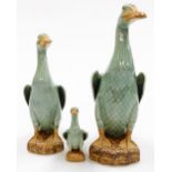 A group of three Chinese celadon glazed models of ducks, each on a rock base with Chinese impressed