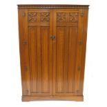 An Elizabethan style oak double wardrobe, with foliate and linen fold carved panelled doors, raised