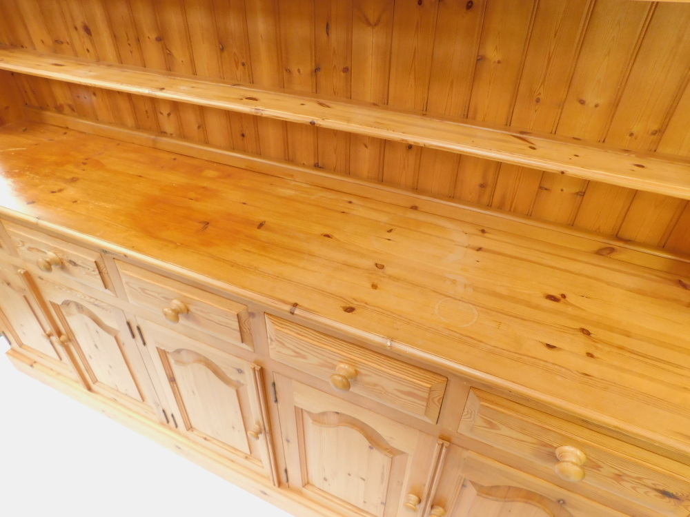 A pine dresser, the outswept pediment over a three shelf plate rack, above five short drawers, over - Image 2 of 4