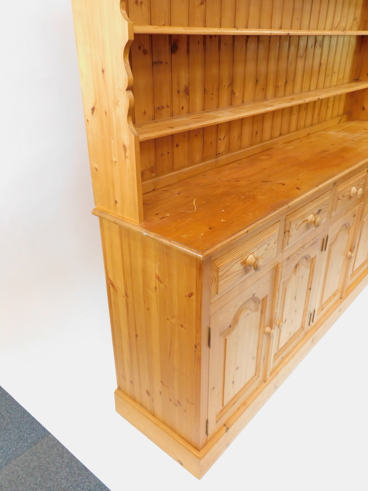 A pine dresser, the outswept pediment over a three shelf plate rack, above five short drawers, over - Image 4 of 4