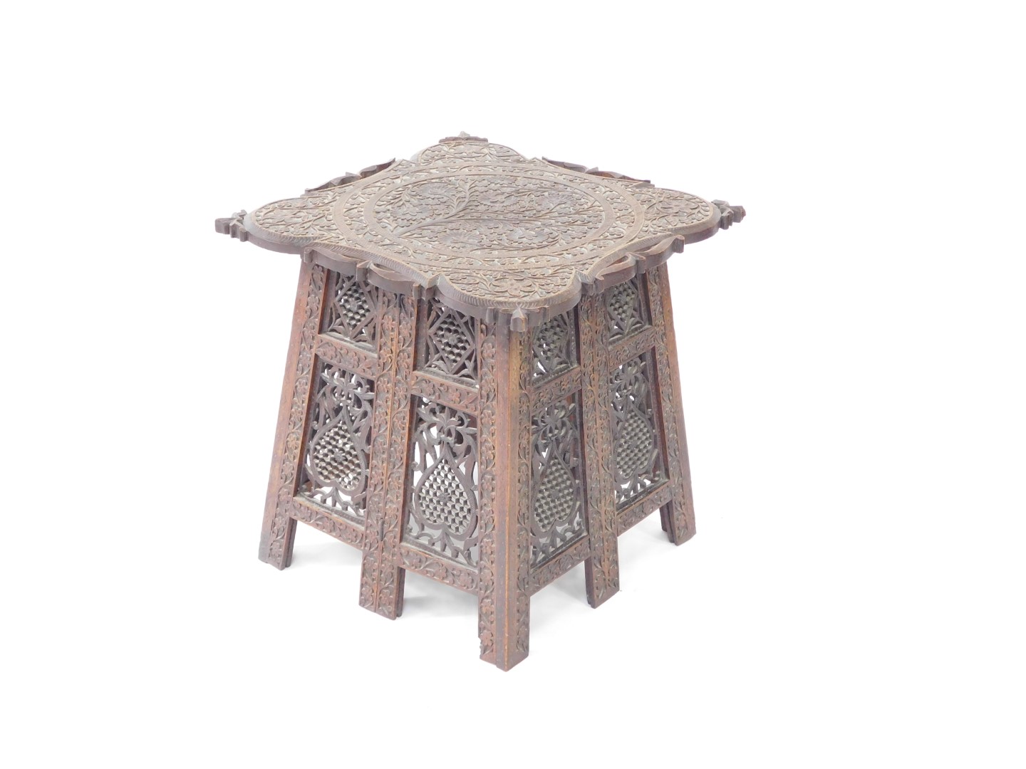 An Indian early 20thC hardwood folding occasional table, the top carved with Arabesques, the sides c