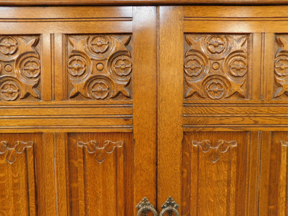 An Elizabethan style oak double wardrobe, with foliate and linen fold carved panelled doors, raised - Image 4 of 4