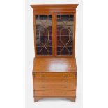 An Edwardian mahogany and satinwood crossbanded bureau bookcase, the outswept pediment over a pair o