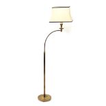 A brass standard lamp, with a curved arm, raised on a loaded circular base, with shade, 150cm high.
