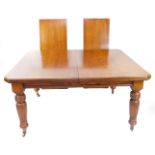 A Victorian oak wind out dining table, with two additional leaves, raised on turned and fluted legs,