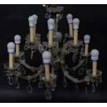 A Continental clear moulded glass two tier twelve branch chandelier, with pear and tear drop shaped