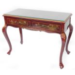 A Chinese painted red lacquer side table, decorated with flowers, with two frieze drawers raised on