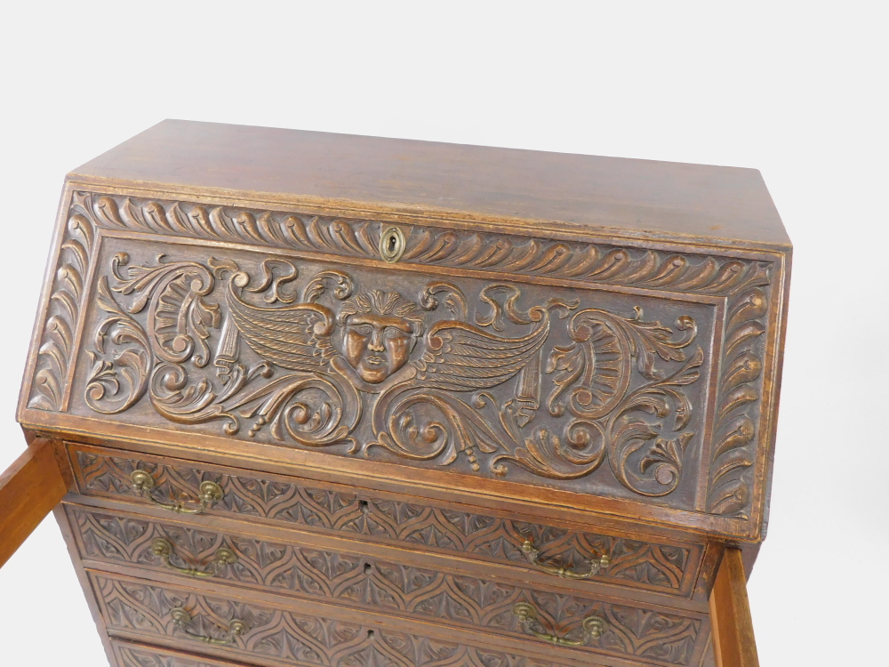 A George III and later carved oak bureau, the fall flap carved with a cherub's head, opening to reve - Image 3 of 4