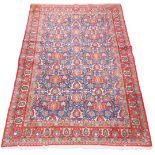 A Kashan rug, blue ground decorated with floral motifs, within a floral border against a red ground,