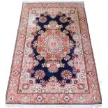 A Pakistan dark blue ground rug, decorated in red, pink and blue with palmettes and floral motifs ar